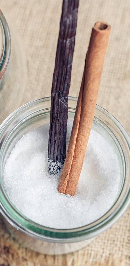 Zimtstange und Vanilleschote in einem Glas Zucker